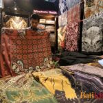 Penjual Batik Wirakuto sedang membentangkan batik untuk pembelinya