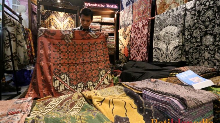 Penjual Batik Wirakuto sedang membentangkan batik untuk pembelinya