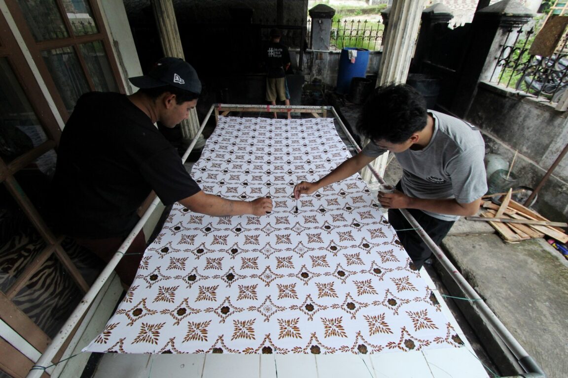 Perajin Batik Sukabumi sedang merapikan hasil cap batik secara manual.