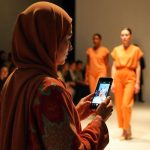 Ilustrasi seorang jurnalis sedang meliput kegiatan fashion show batik.