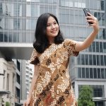 Seorang remaja mengenakan batik sedang selfie untuk feed instagram-nya.