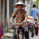 Ilustrasi penjual batik tempo dulu berkeliling menawarkan kain batik.