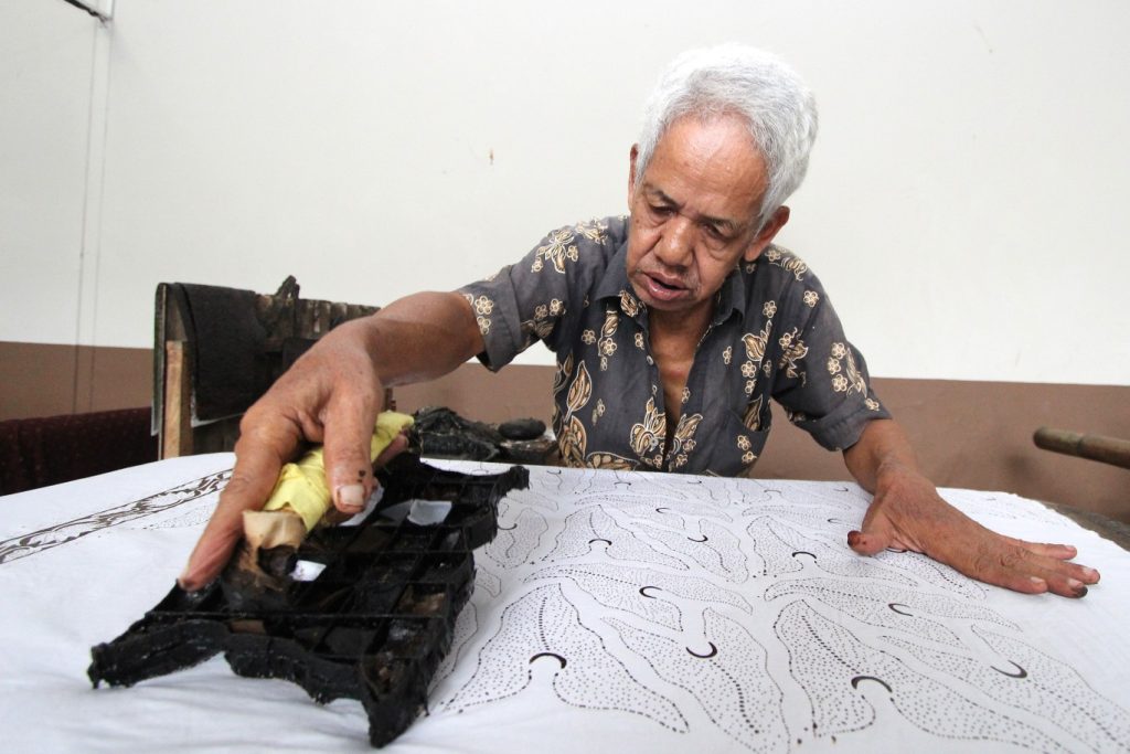 Seorang perajin batik Banyumas sedang membuat motif menggunakan cap di kain batik