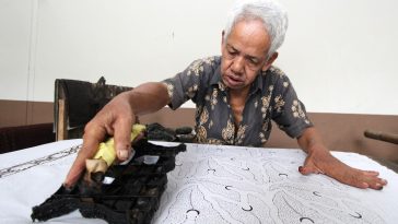 Seorang perajin batik Banyumas sedang membuat motif menggunakan cap di kain batik