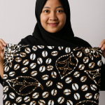 gambar wanita cantik Indonesia menggunakan hijab sambil membentangkan kain batik belitung motif biji kopi