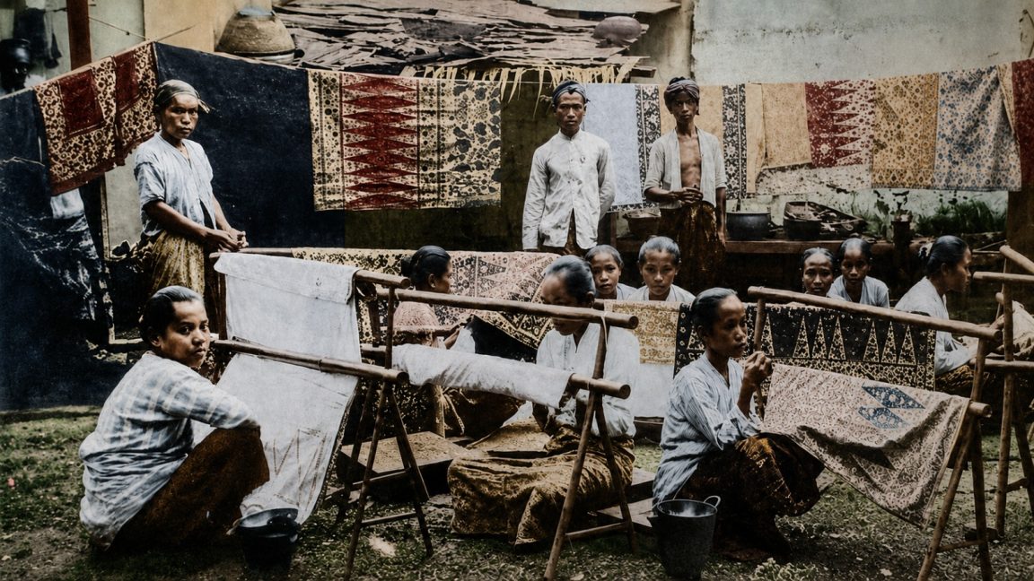buat gambar foto ukuran 16:9. Konsep foto: Seorang gadis Indonesia menggunakan kain dodot ditutupi selendang warna kuning sedang merentangkan kain putih dengan motif batik belum jadi di gawangan. Masa itu era tahun 1930-an.