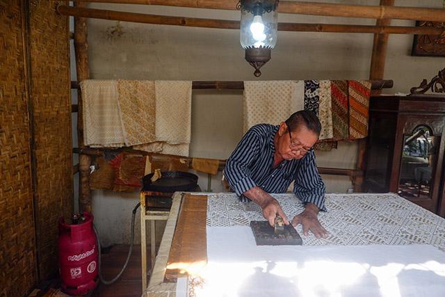 Batik cap modular dengan inspirasi Kampung Naga diterapkan pada kain panjang dan scarf sebagai produk tekstil kontemporer.