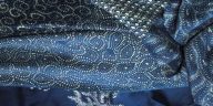 Teknik batik indigo menggunakan daun Indigofera tinctoria melalui fermentasi, reduksi, pencelupan dan pelorodan untuk menghasilkan warna biru.