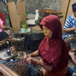 Motif Batik Sukoharjo jamu gendhong memadukan figur mbok jamu, rempah, buketan, kembangan, dan isen-isen dengan warna sogan klasik setempat.
