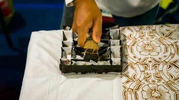 Sablon batik dikombinasikan dengan teknik cap menggunakan balok kayu untuk menghasilkan motif kontemporer pada kain produk fashion modern.